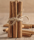 Bundled cinnamon sticks tied with twine on a wooden surface
